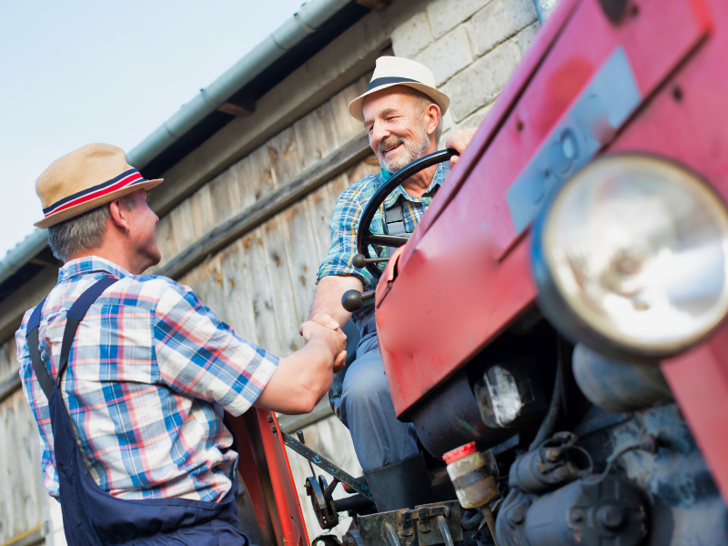 man shaking another man's hand on tractor